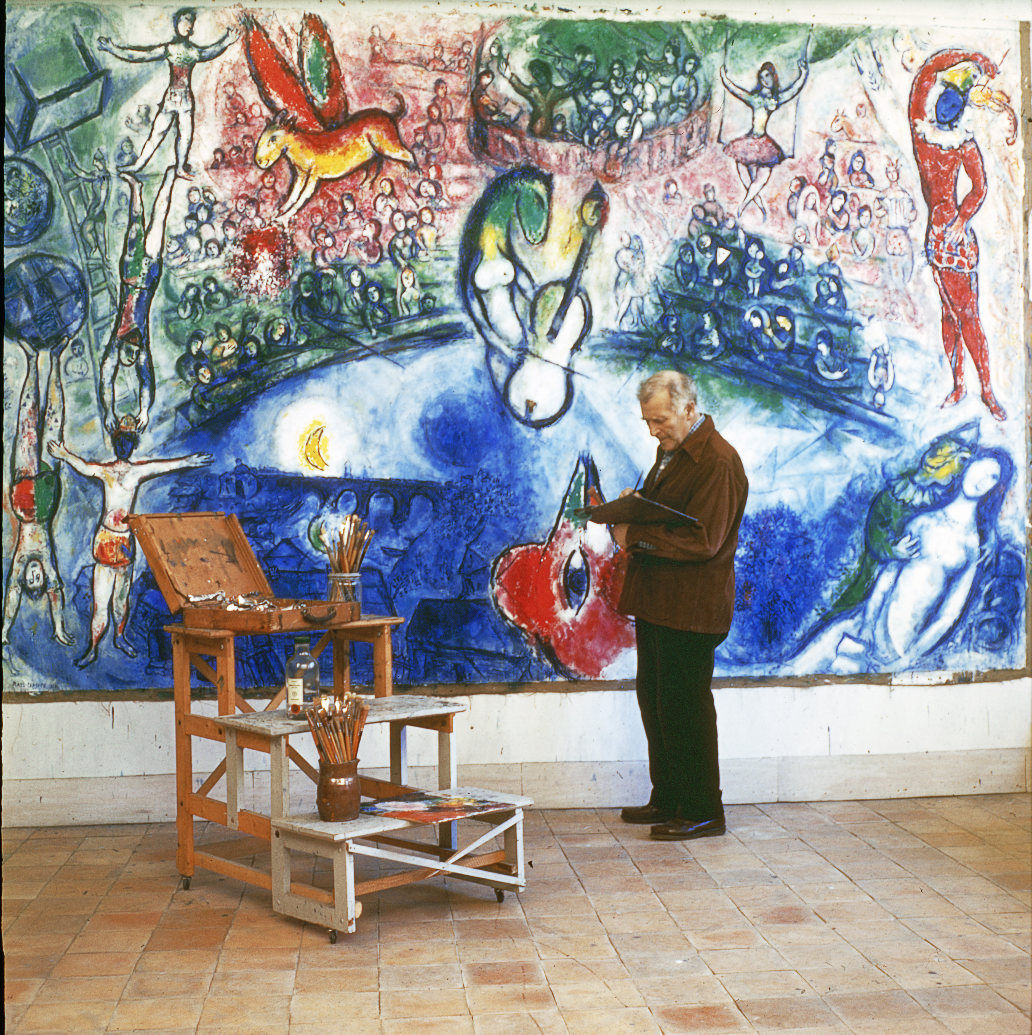 Marc Chagall standing infront of one of his paintings