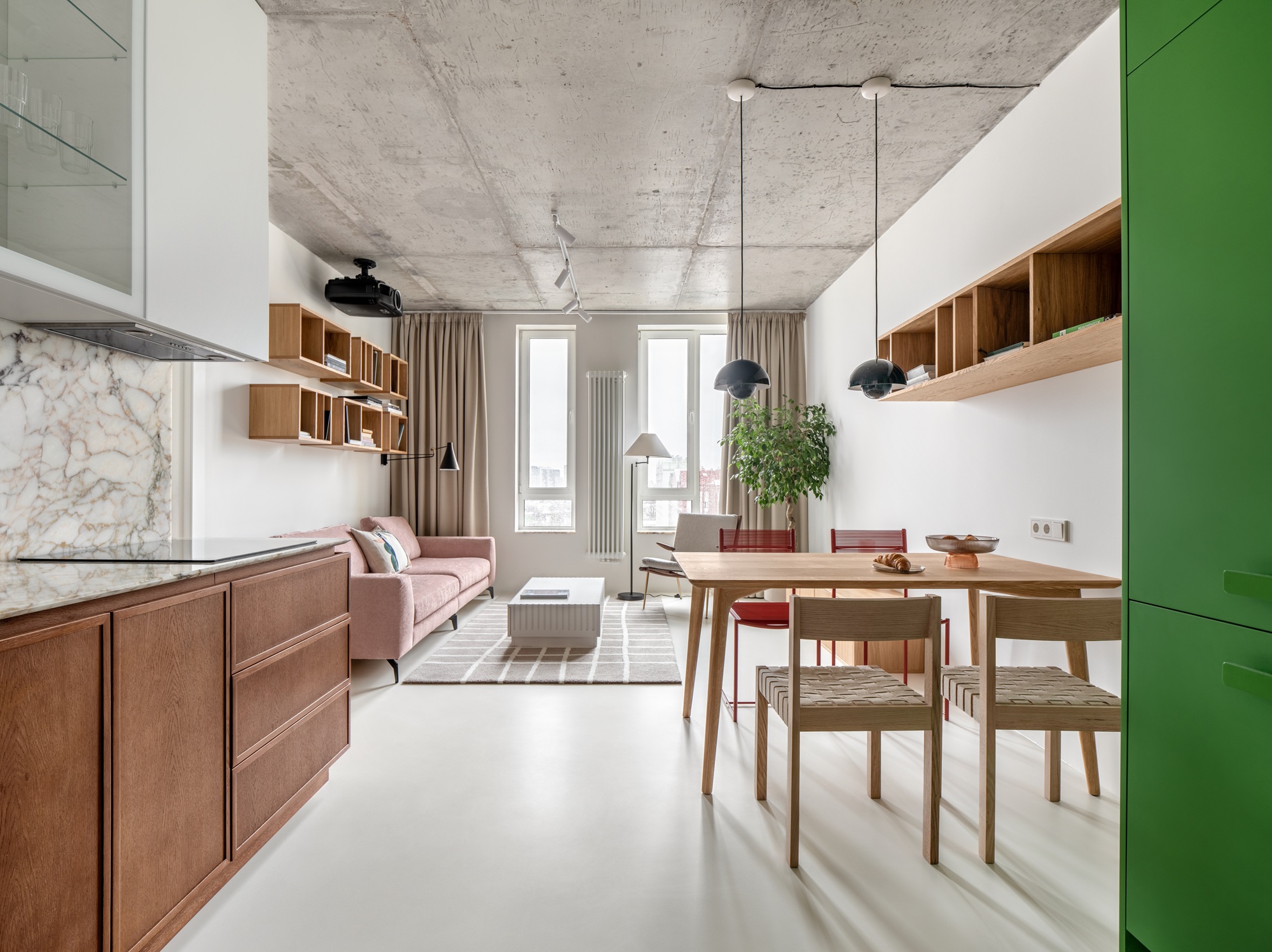 an apartment with a wood and marble kitchen and green cabinets on the other side, with a concrete ceiling