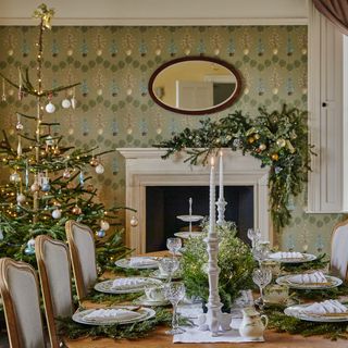 Dining table laid for christmas with natural centrepiece and christmas tree beside