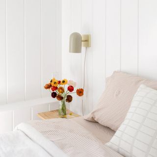 A plug in sconce next to a bed
