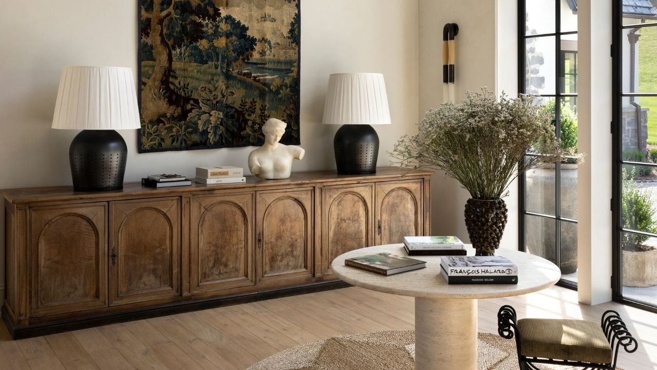 light bright neutral entryway with light walls and floor with a large rustic credenza sitting beneath a large antique tapestry 