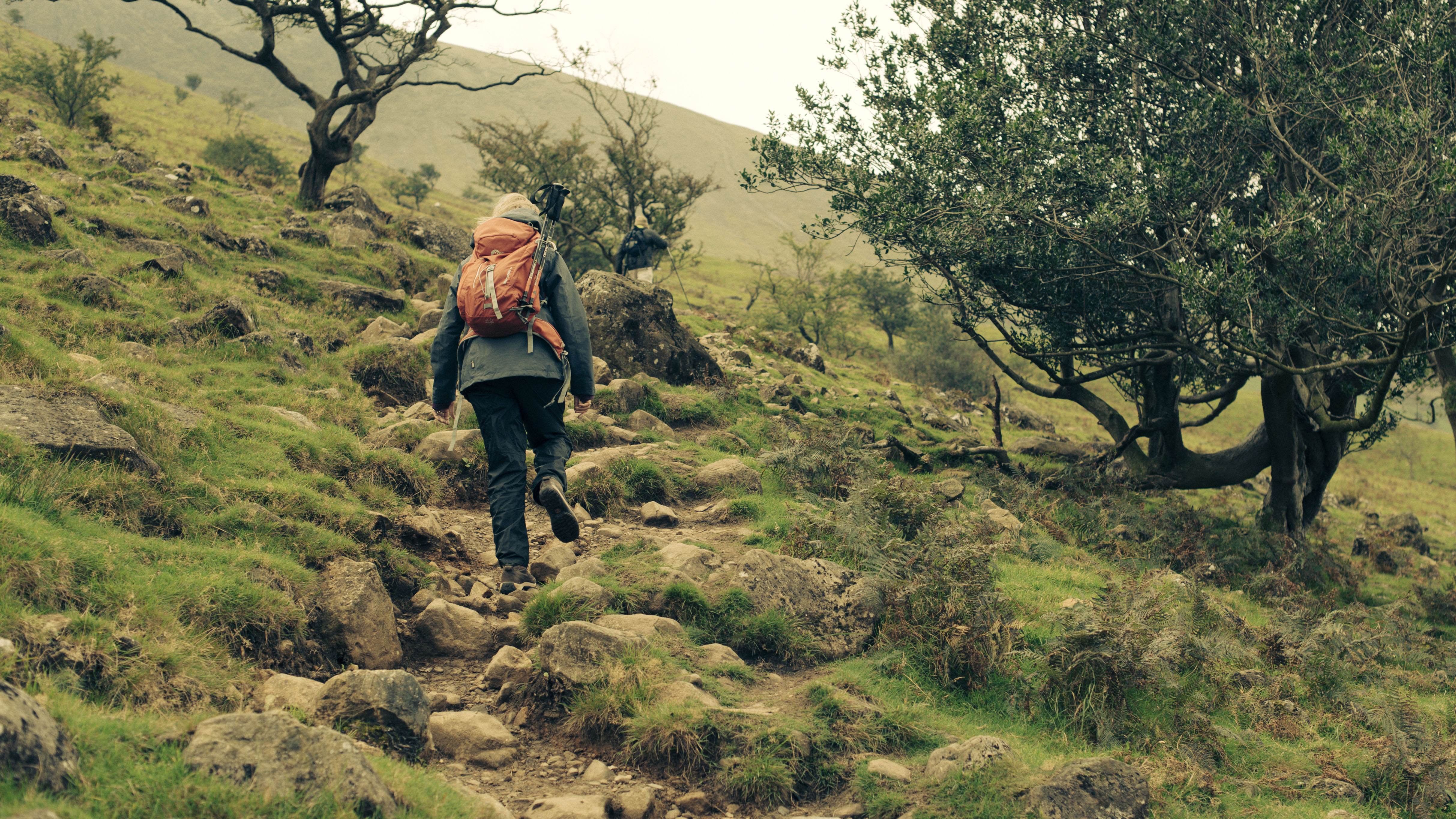 The image shows a person hiking on undulating terrain