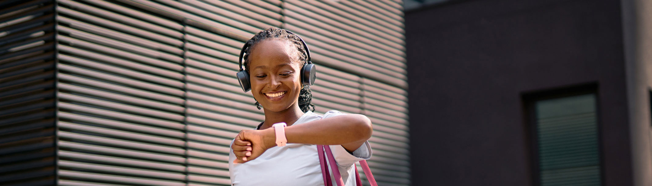 A picture of a young woman smiling while looking at her smartwatch