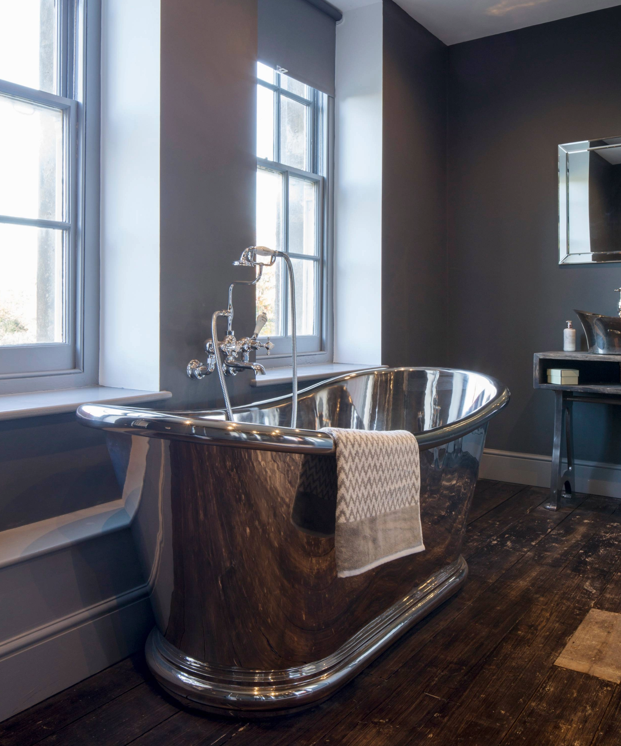 Dark bathroom idea with silver freestanding bath and grey walls