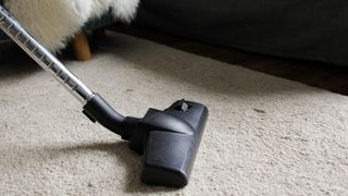 person vacuuming a beige carpet