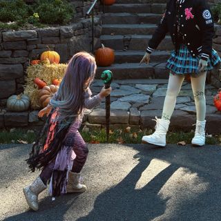 Khai Malik wearing a purple wig and glittery boots walking outside on Halloween