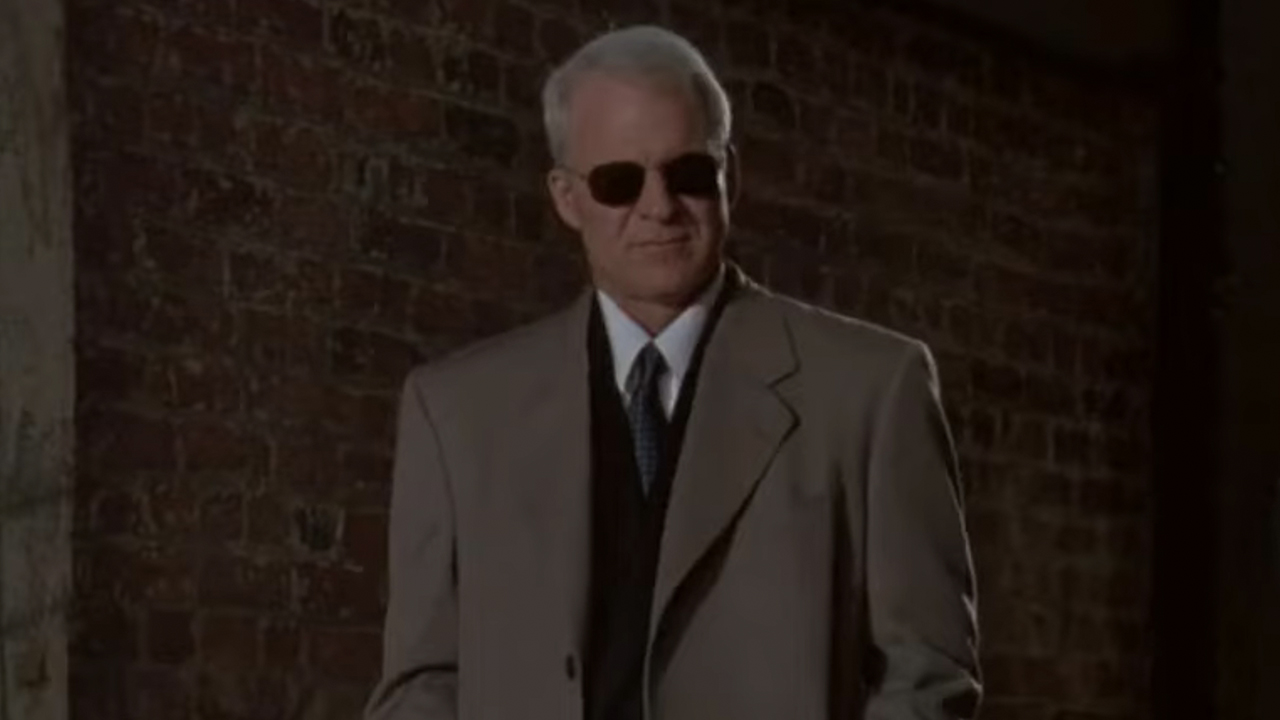 Steve Martin in a stylish suit and coat, wearing sunglasses in The Spanish Prisoner