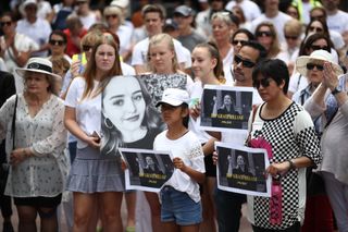A crowd of people holding photos of Grace Millane to pay tribute to her