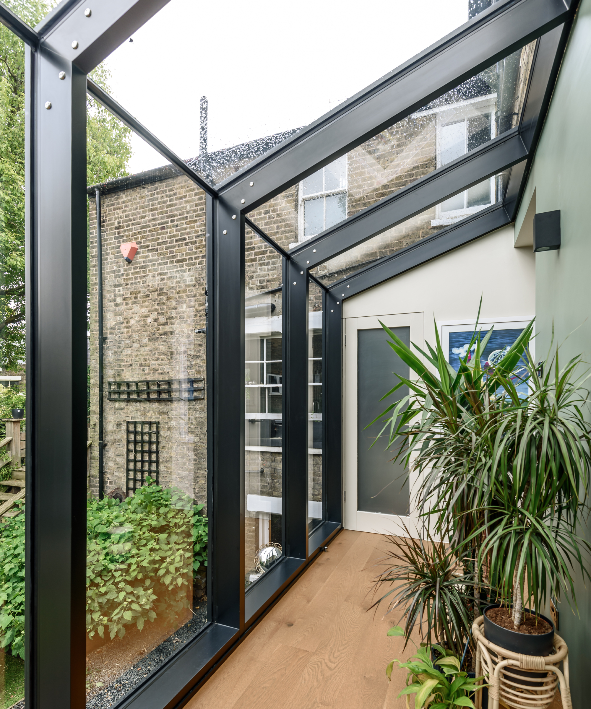 lean to glass extension with metal framework separating glass panels on walls and roof