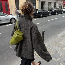 Poppy Almond wearing a bright green bag and fall coat.