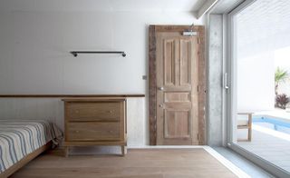 A white room with beige flooring, furniture, door and glass sliding door
