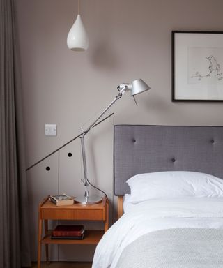 A gray bedroom with a white pendant ceiling light and a table lamp