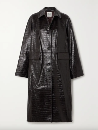 a croc trench coat from toteme on a plain backdrop