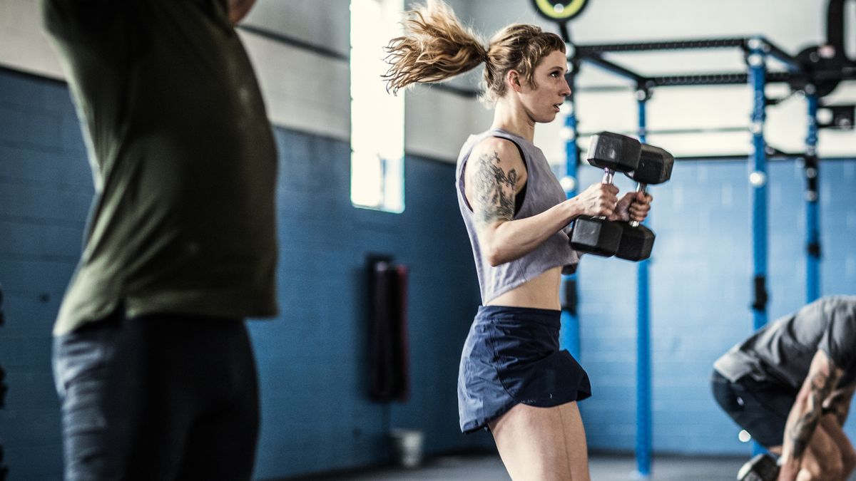 Woman performs hang clean with two dumbbells