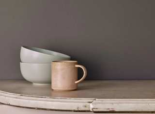 taupe paint on wall with coffee mug and bowls on a shelf in the foreground