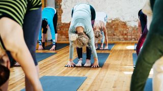 Woman stretching down towards feet in yoga class