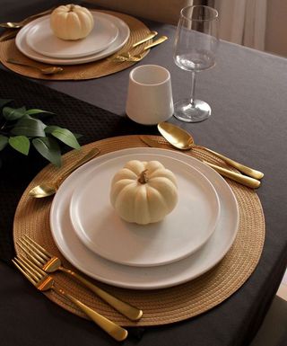 White pumpkin on white plates with gold silverware surround