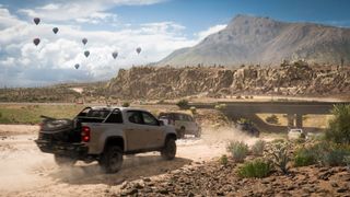 meilleurs jeux Xbox Game Pass : plusieurs voitures roulant sur une route poussiéreuse dans le désert, avec des montagnes escarpées au loin.