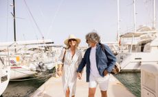3EDC0PM Happy senior couple holding hands, enjoying a summer holiday walking along the harbor