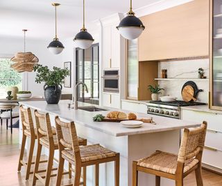 kitchen with white walls and cabinets and rattan bar stools with wooden floors