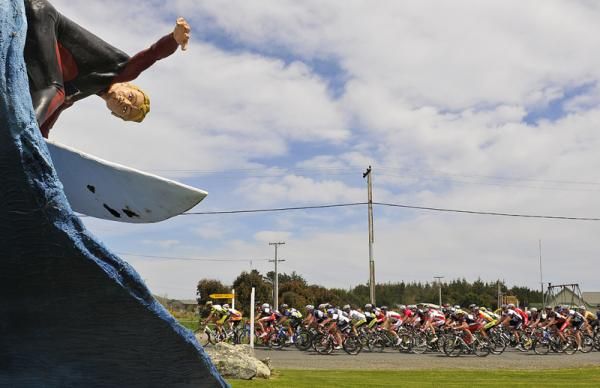 A surfer drop in as the peloton pass through Colac bay.