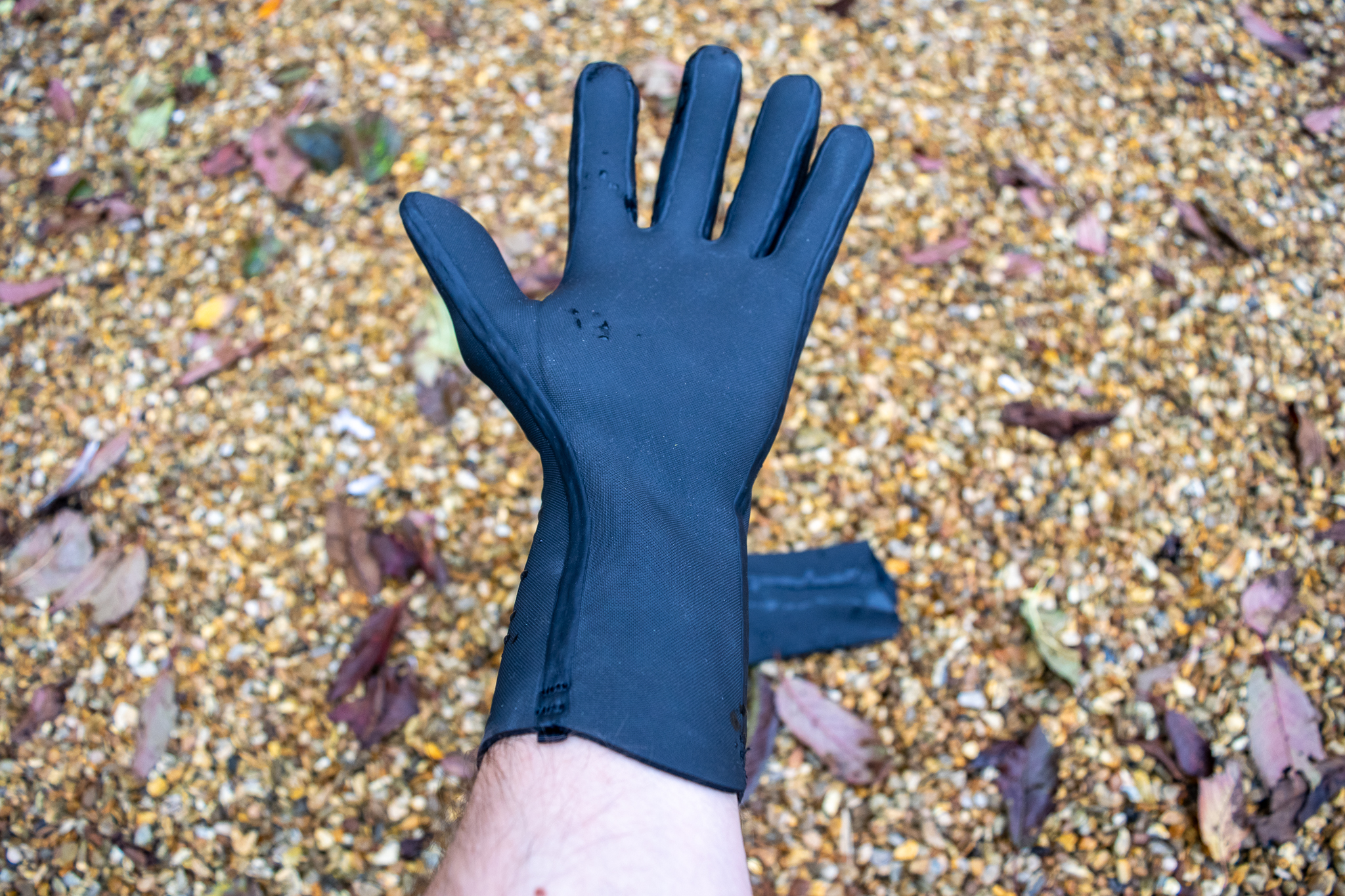 Velotoze neoprene gloves on some gravel with water droplets on them