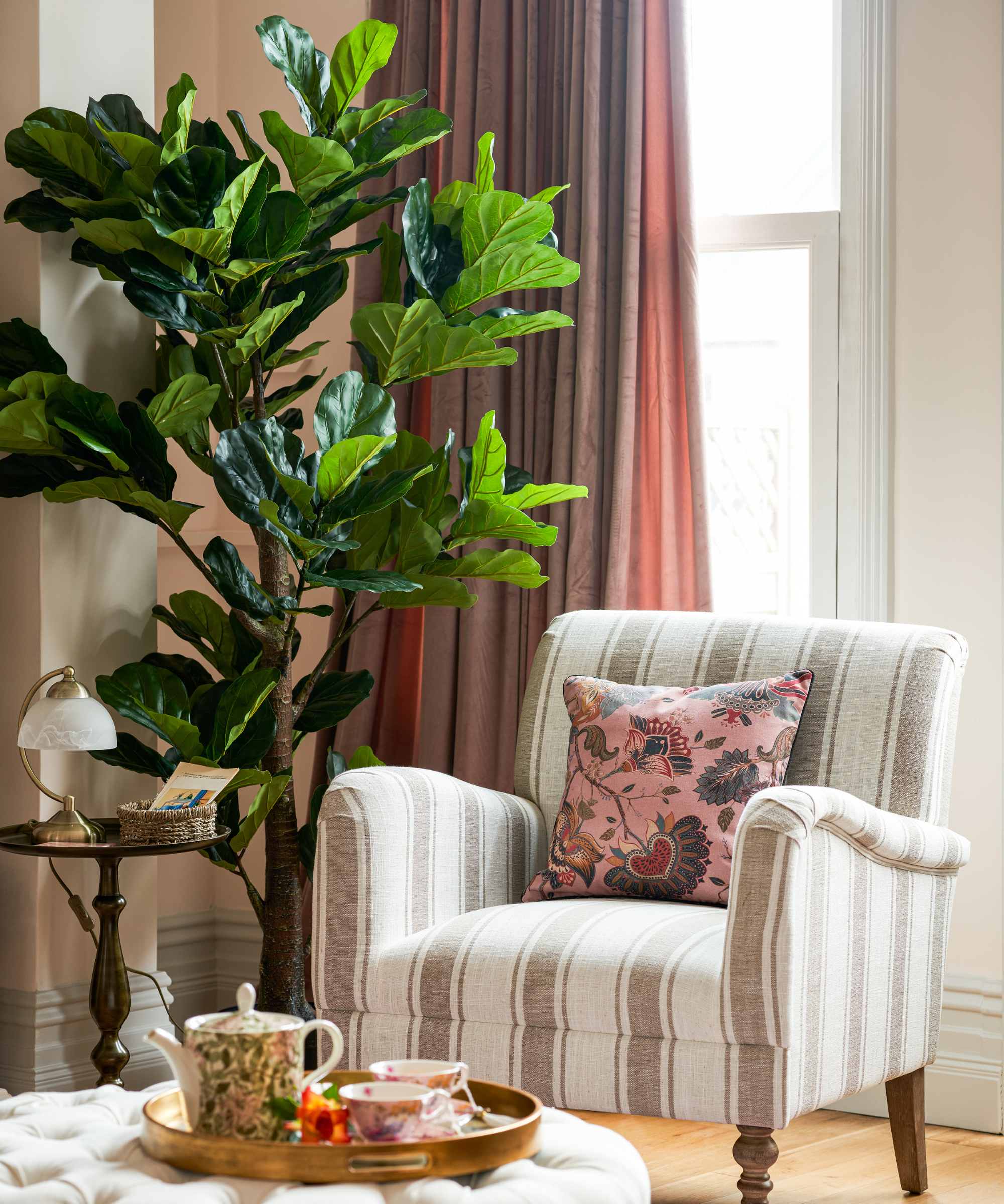 reading nook with striped arm chair in front of a window with a plant beside it