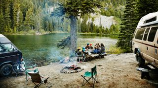 Friends sharing a meal while camping by lake