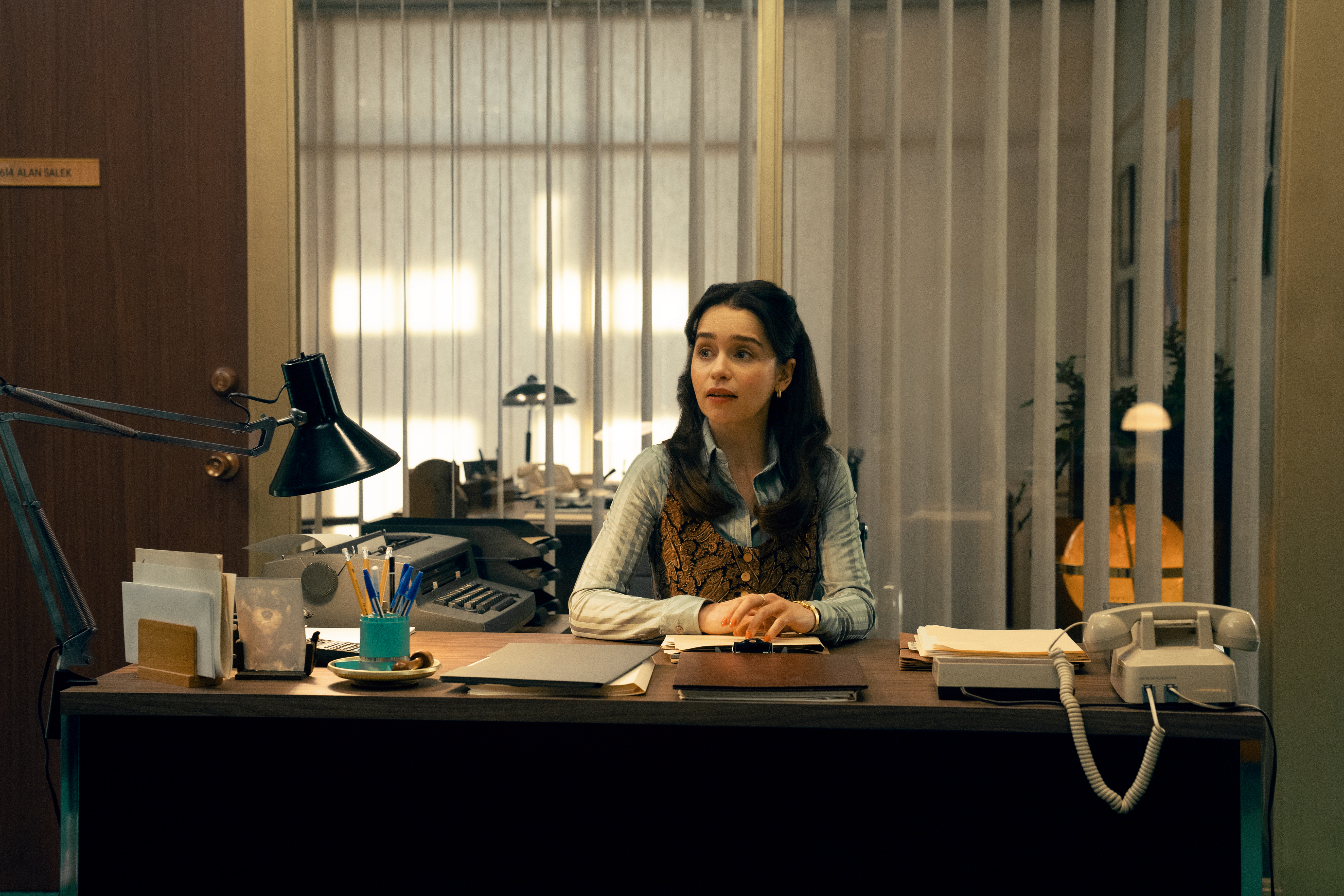 A series of film stills and photographs from a 1970s-inspired set featuring vibrantly decorated interiors with layered furniture and warm lighting, along with characters dressed in vintage clothing whether indoors or at parks and markets outdoors.