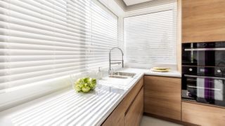 A modern kitchen with the blinds closed in the windows