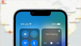 SOS service indicator shown on iPhone in front of a blurred map showing network outage hotspots