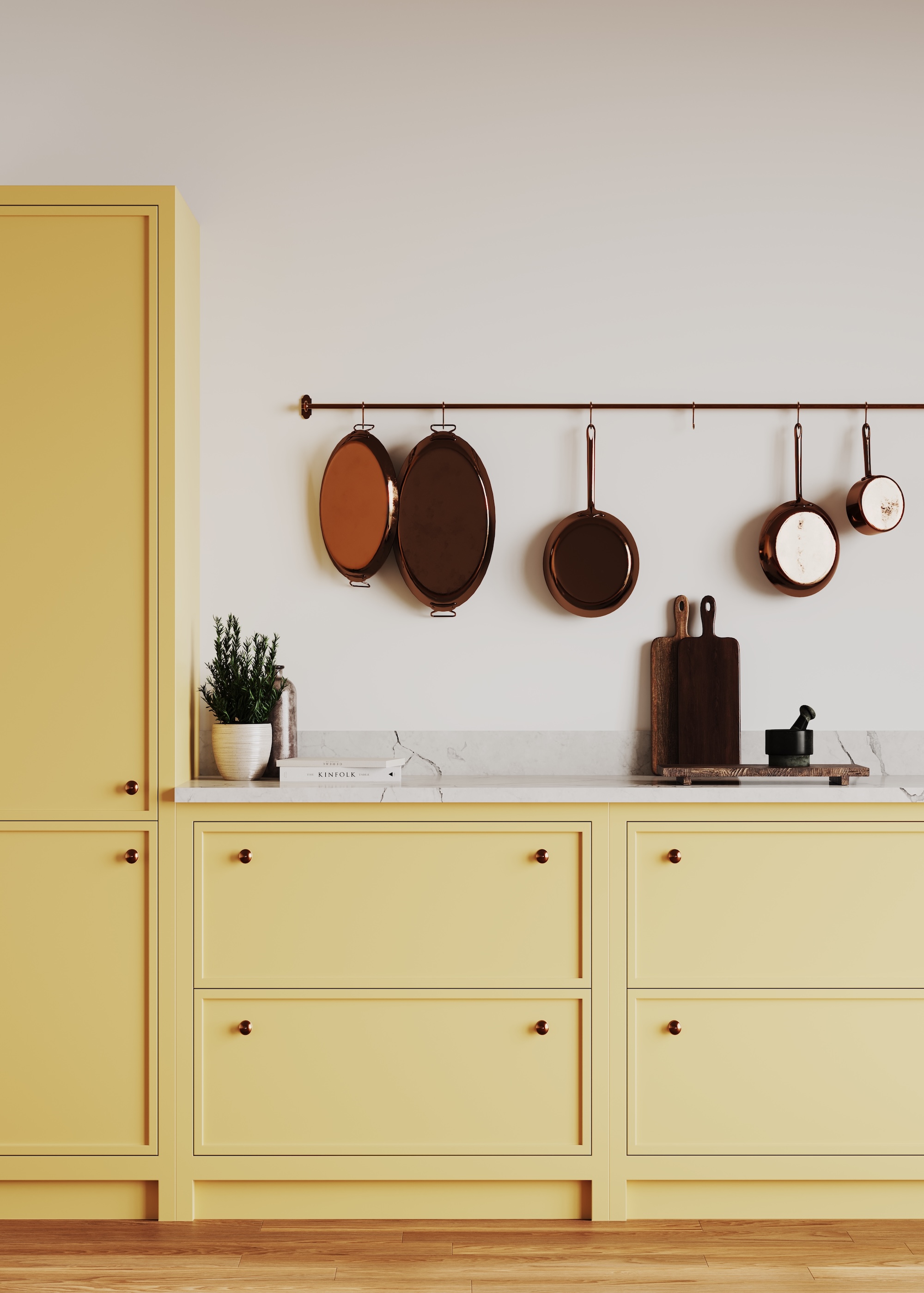 pale yellow kitchen cabinets with skinny Shaker style framing and small door knobs with pale marble worktops and a hanging rail with pots and pans