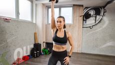 A woman performing single arm dumbbell overhead press