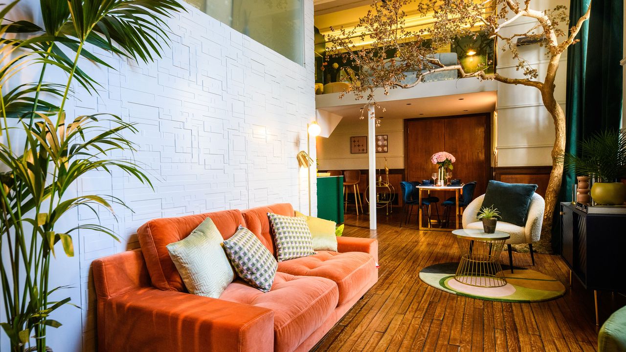 Orange couch with yellow cushions an indoor tree and gilded accents