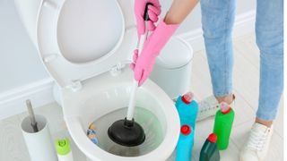 Person unclogging a blocked toilet with plunger