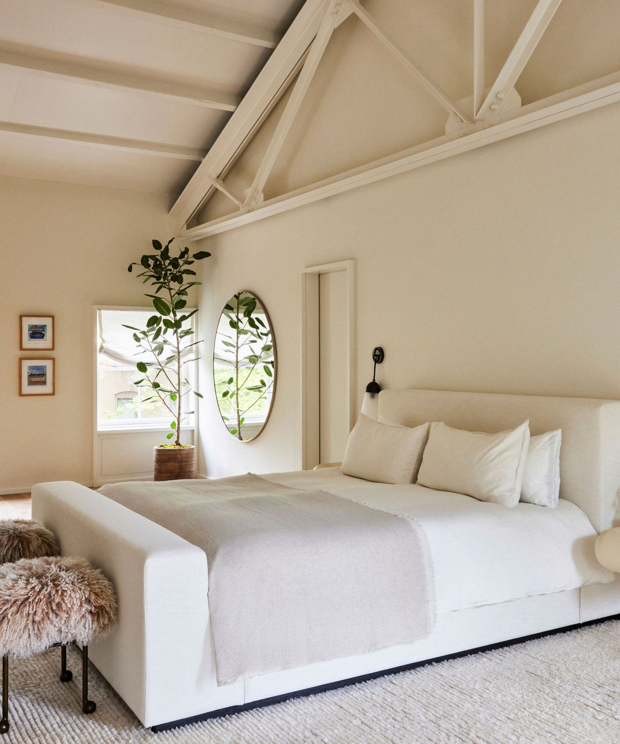 A brownstone bedroom with raftered ceilings and a large white bed