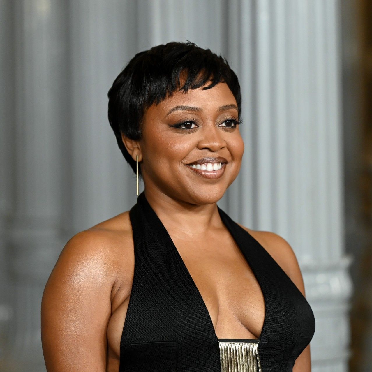 a black woman with short hair posing for paparazzi at a red carpet event