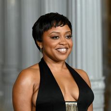 a black woman with short hair posing for paparazzi at a red carpet event