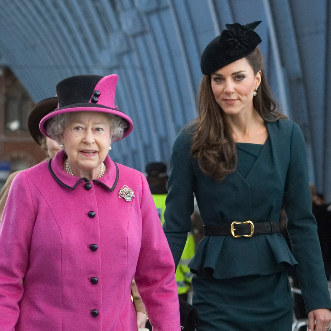 Queen Elizabeth wearing a pink coat and hat walking next to Princess Kate