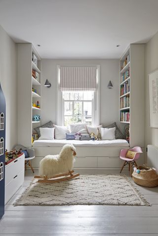 A kids bedroom with a built-in bed with bookshelves, a white rug, and a wicker basket storing toys