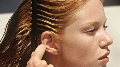 Ginger woman coming her hair through with sunscreen for scalp 