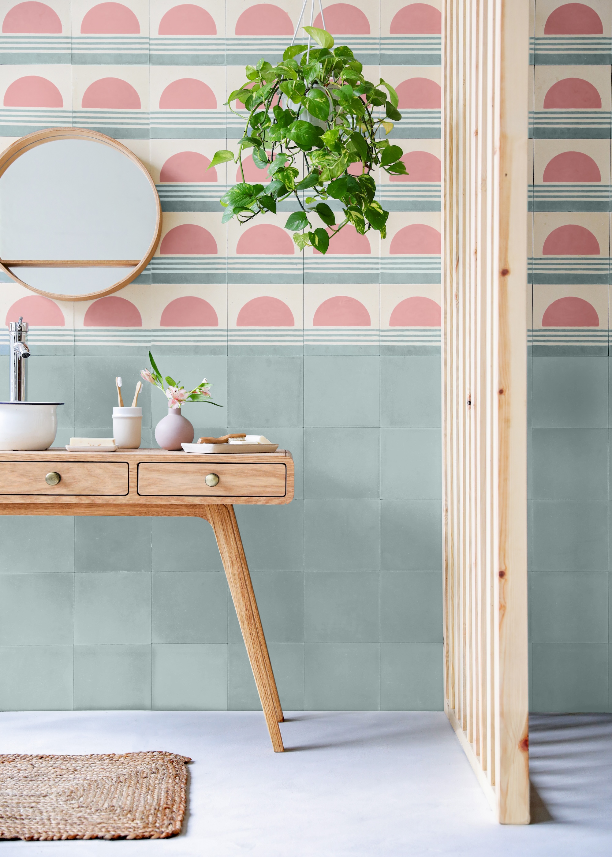 A colorful bathroom with pink and blue tiling. There is also a vanity in the toilet with a sink and a mirror above it.