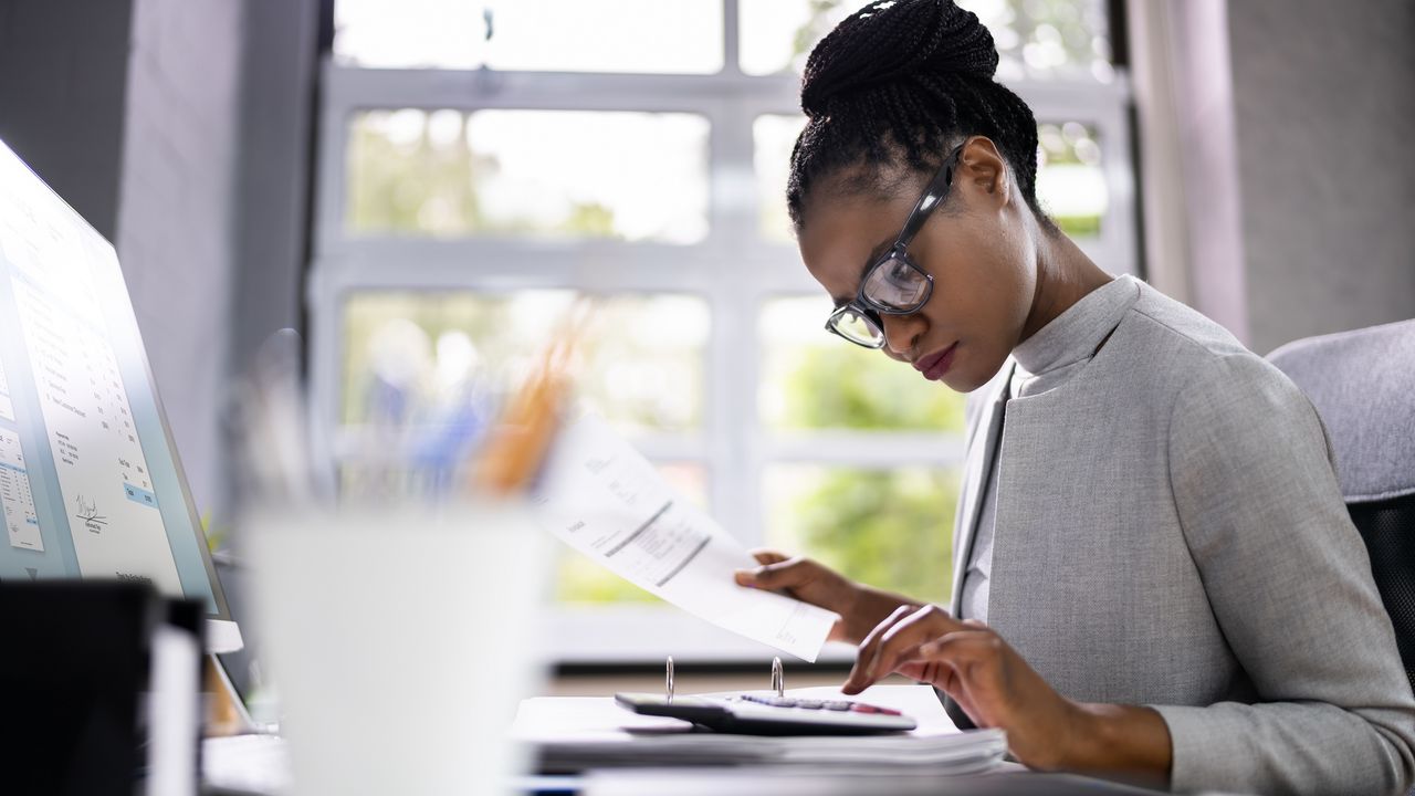 A woman uses a calculator while sitting at her desk. 