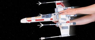 Lego UCS X-Wing Starfighter being played with in front of a space background 