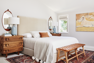 A bedroom with white sheets and a cream headboard