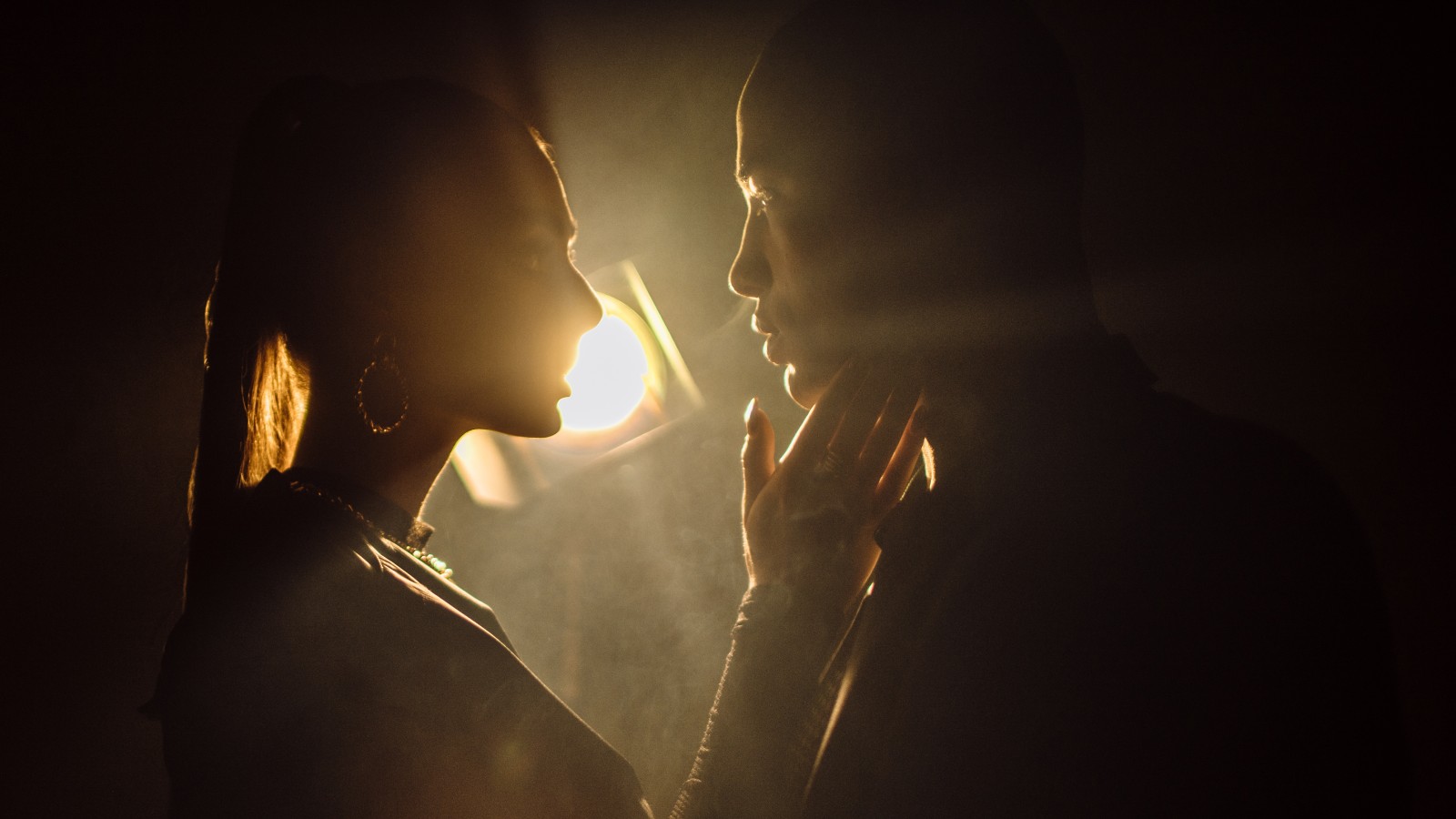 Sensuous Young Woman Close to Kiss Man Against Light Background. Silhouette of man and woman closing to kiss.