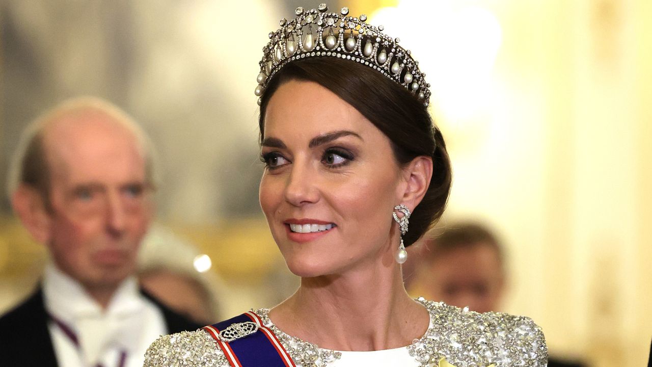 Kate Middleton wearing a tiara and white and silver evening gown looking to the left