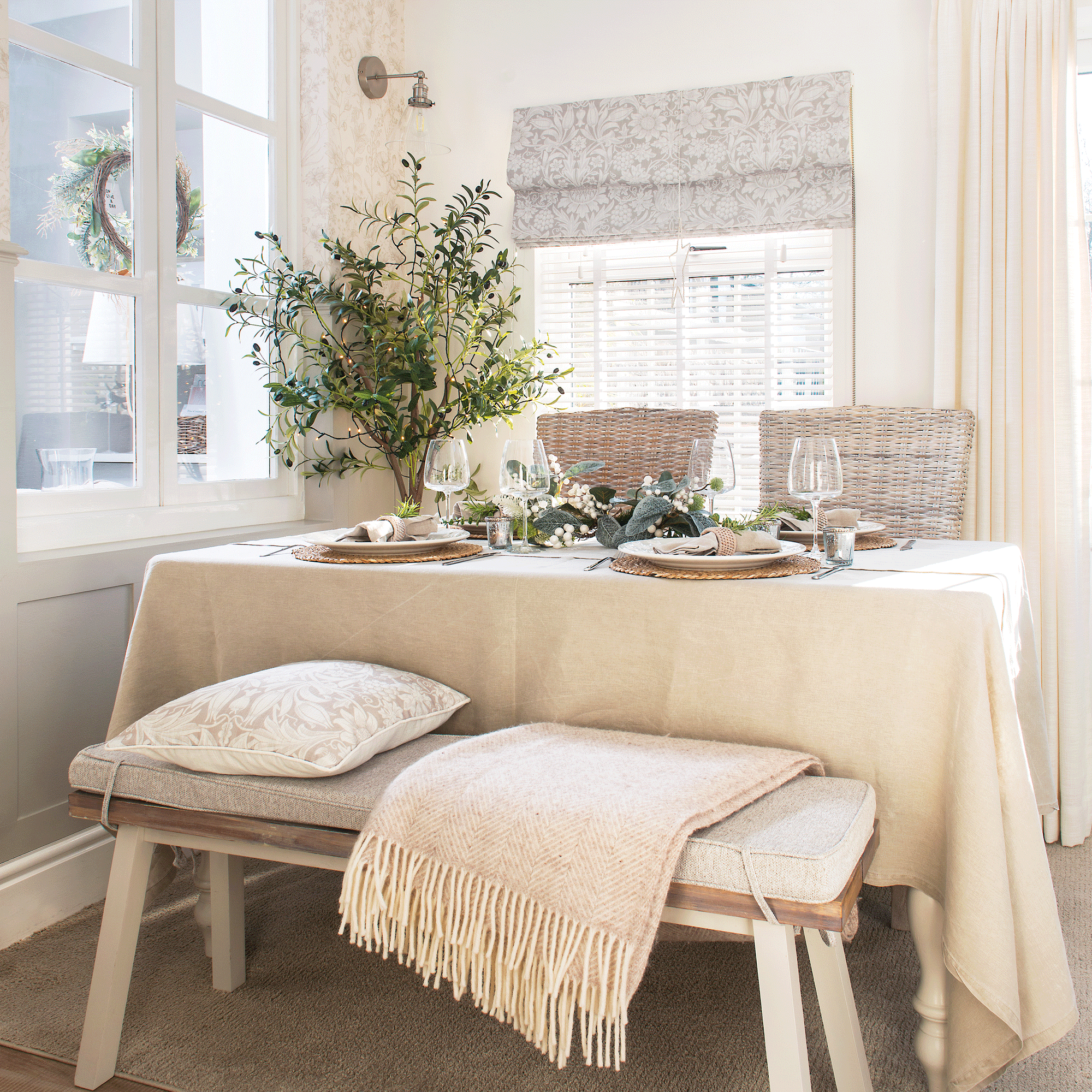 a neutral coloured dining area in a kitchen with bench seating an linen tablecloth