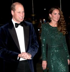 Kate Middleton wearing a green beaded gown walking next to Prince William in a tux