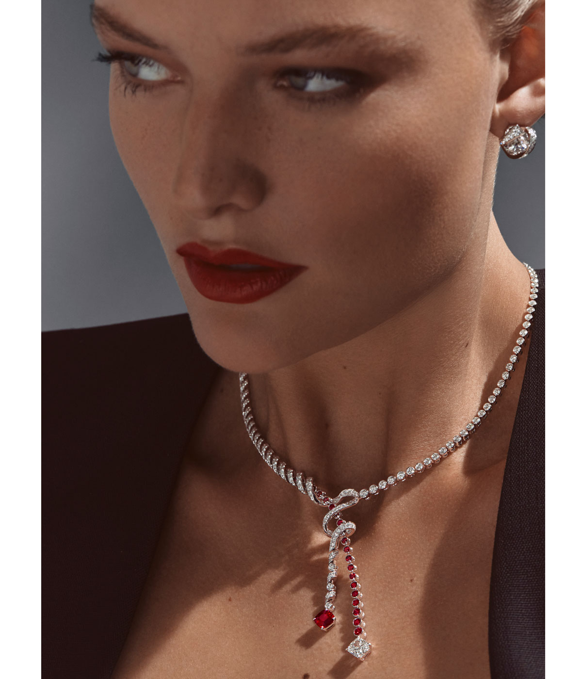 Woman wearing diamond earrings and a diamond and ruby necklace